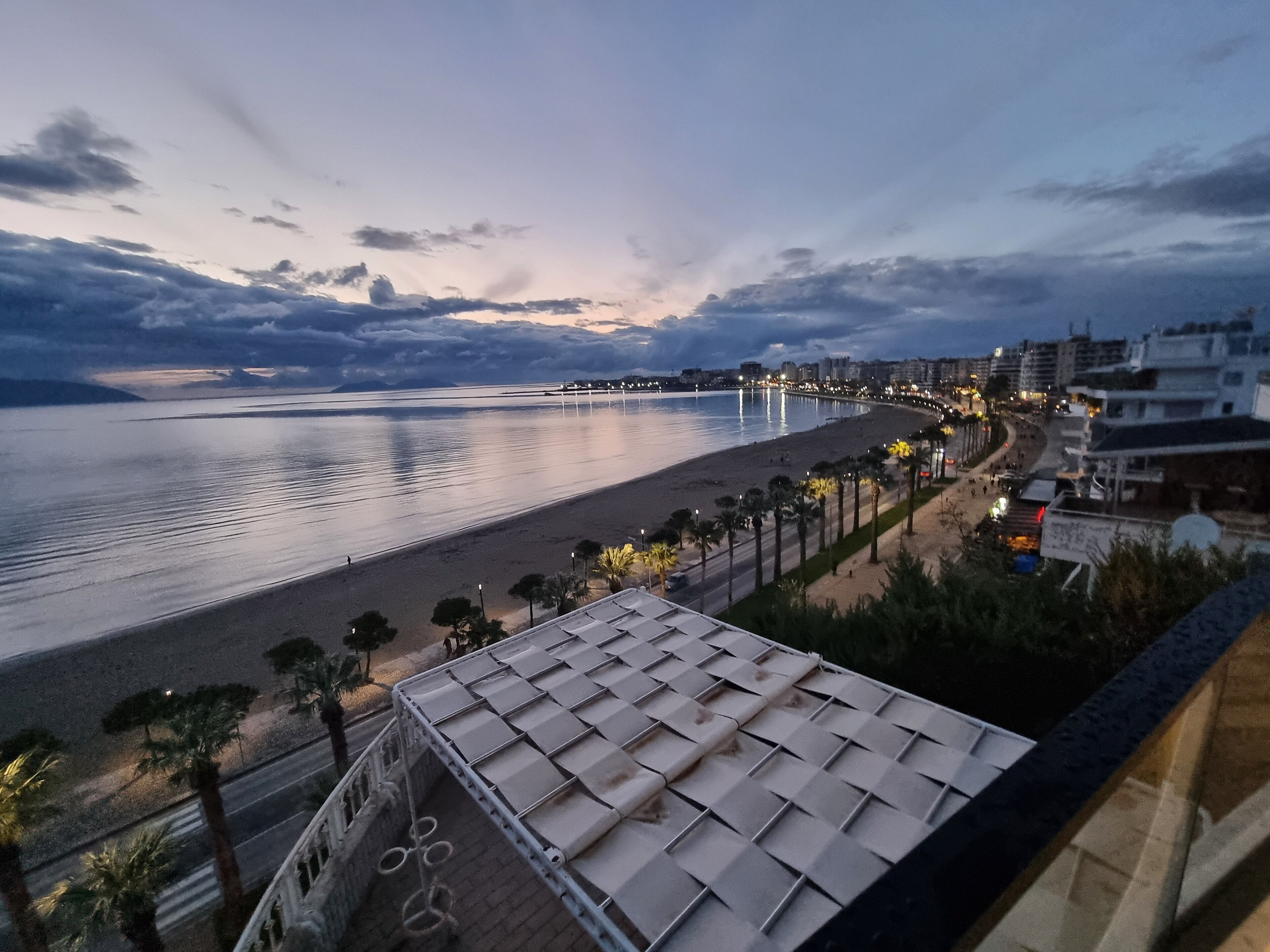 Vista costera con playa, paseo marítimo y edificios a lo largo de la orilla.