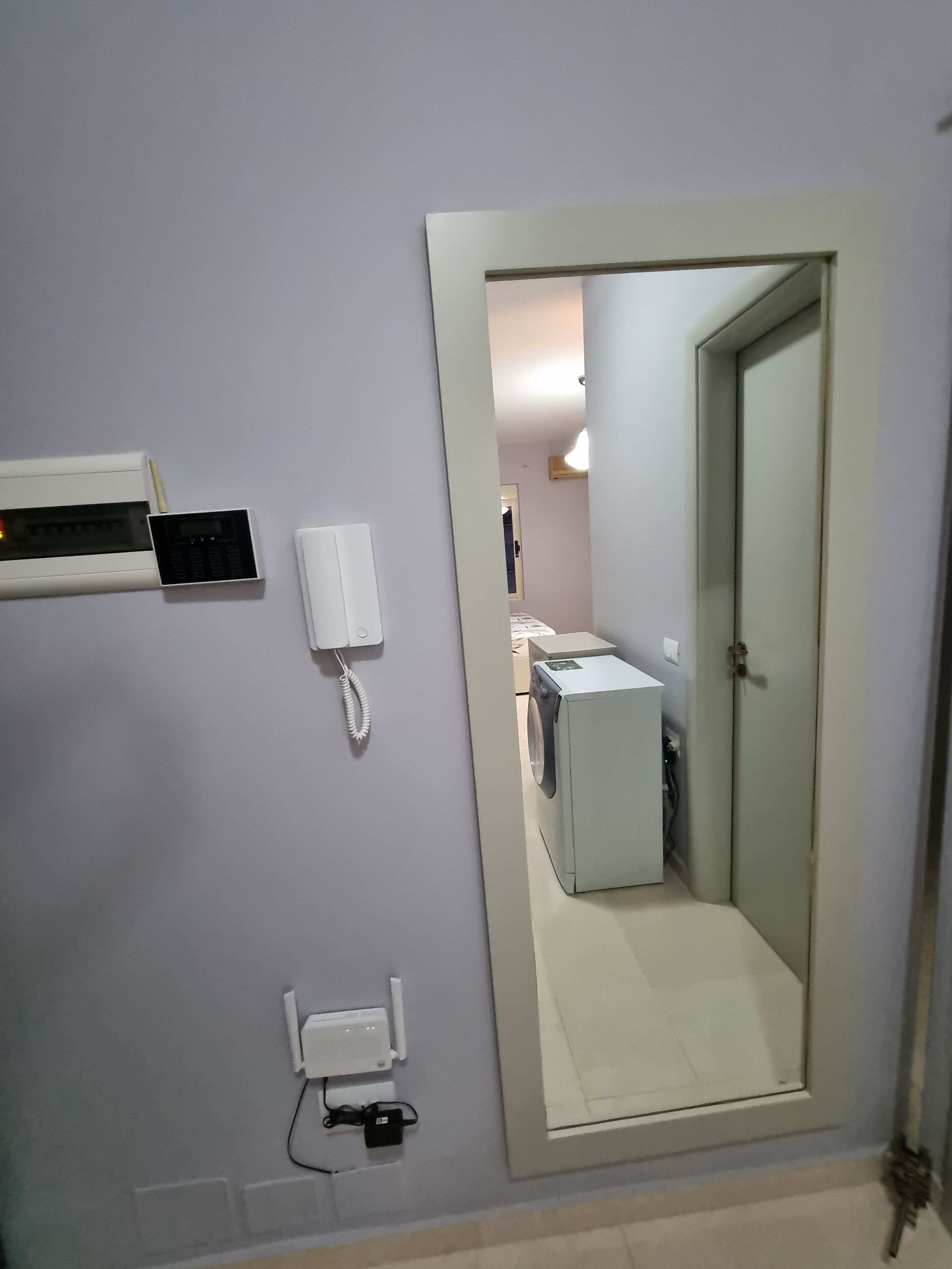 A room with a washing machine, a telephone, and a wall-mounted device.