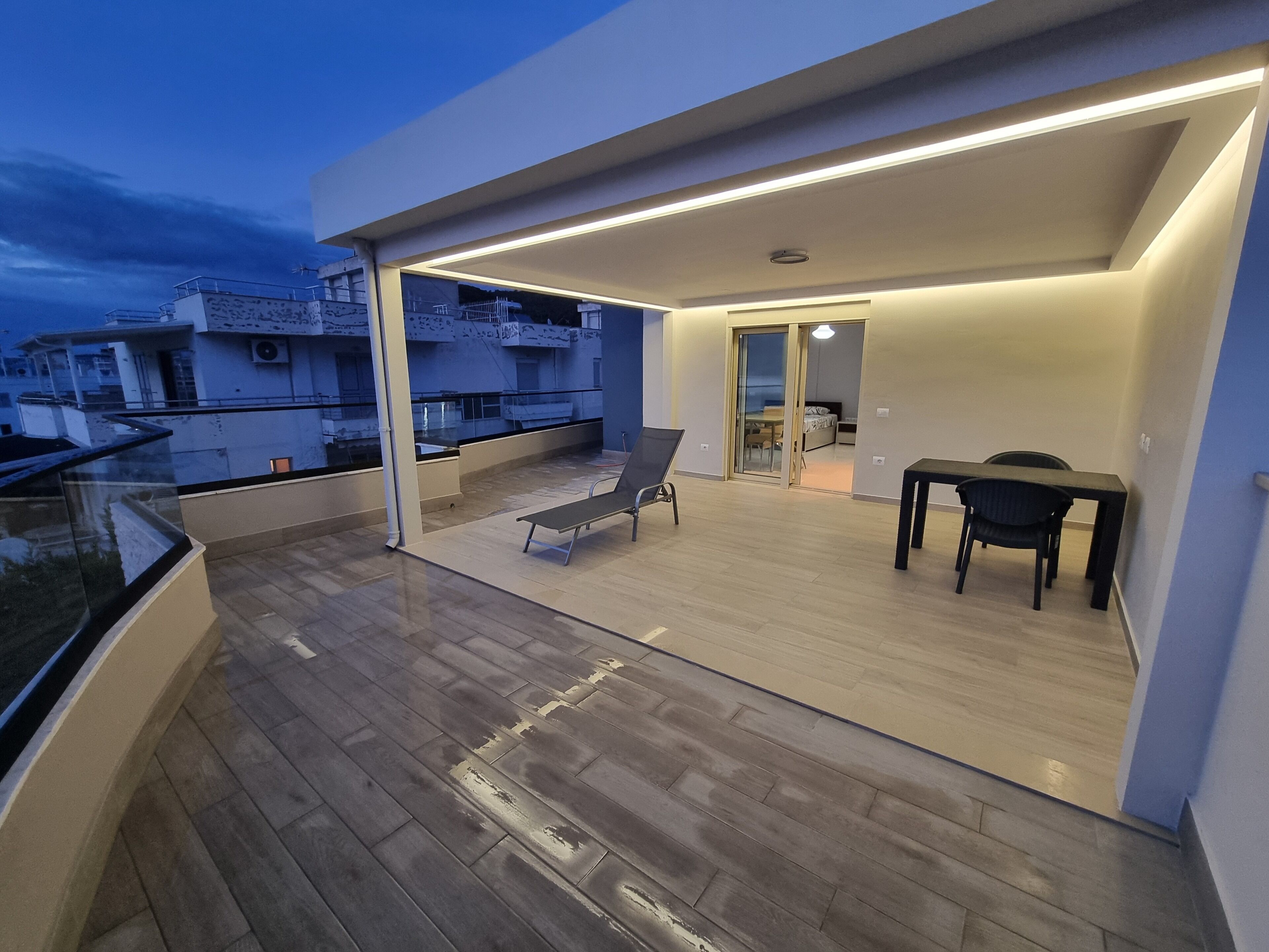 A modern apartment with a balcony, a dining area, and a view of neighboring buildings.