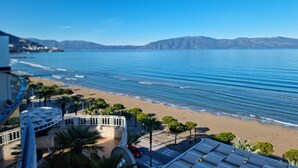 Une vue côtière avec une plage, l’océan et des montagnes au loin.