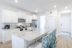 Enjoy cooking in this well-equipped kitchen with a central island, sink, and ample storage.