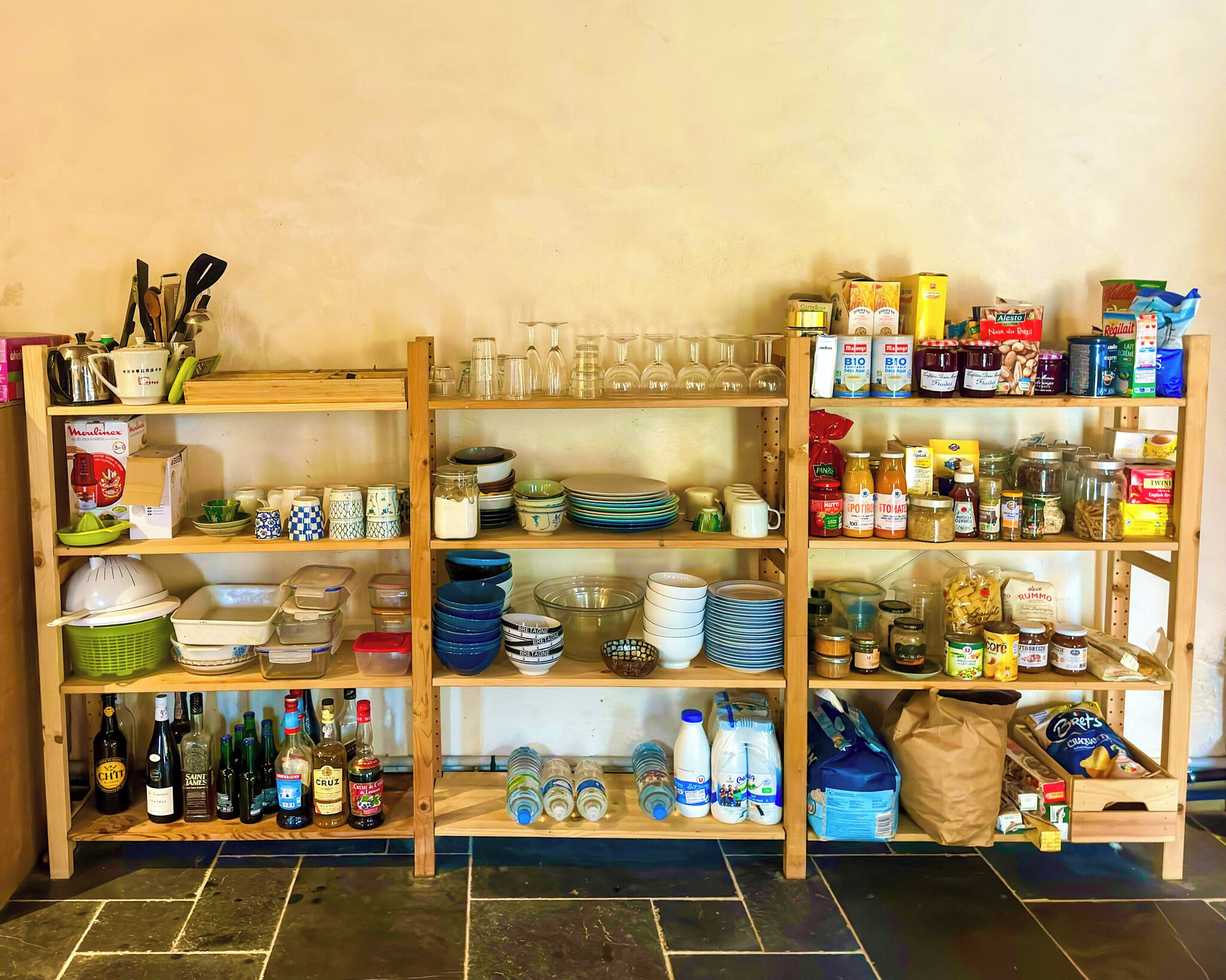 A kitchen pantry stocked with various food items, kitchenware, and beverages.