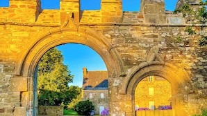 An old stone archway leading to a building with a wooden gate. - Métairie du Hellès (Lanmeur)