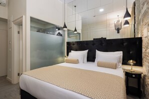 Una habitación de hotel moderna con una cama grande, cabecera oscura e iluminación colgante.
