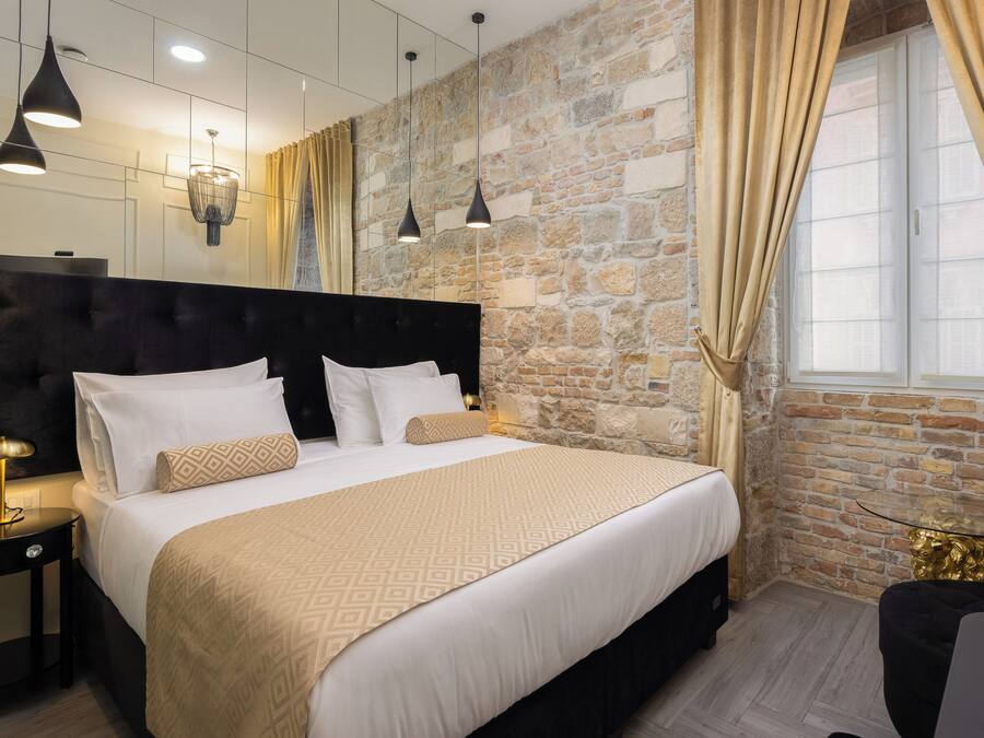 Un dormitorio moderno con una cama grande, cabecera y pared de piedra.