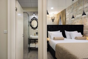 Una habitación de hotel moderna con una cama grande, un baño con ducha de vidrio y una pared de acento de piedra.