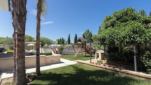 A backyard with a wooden playset, a small garden area, and a palm tree. - Casa Torre Specchio (Bari)