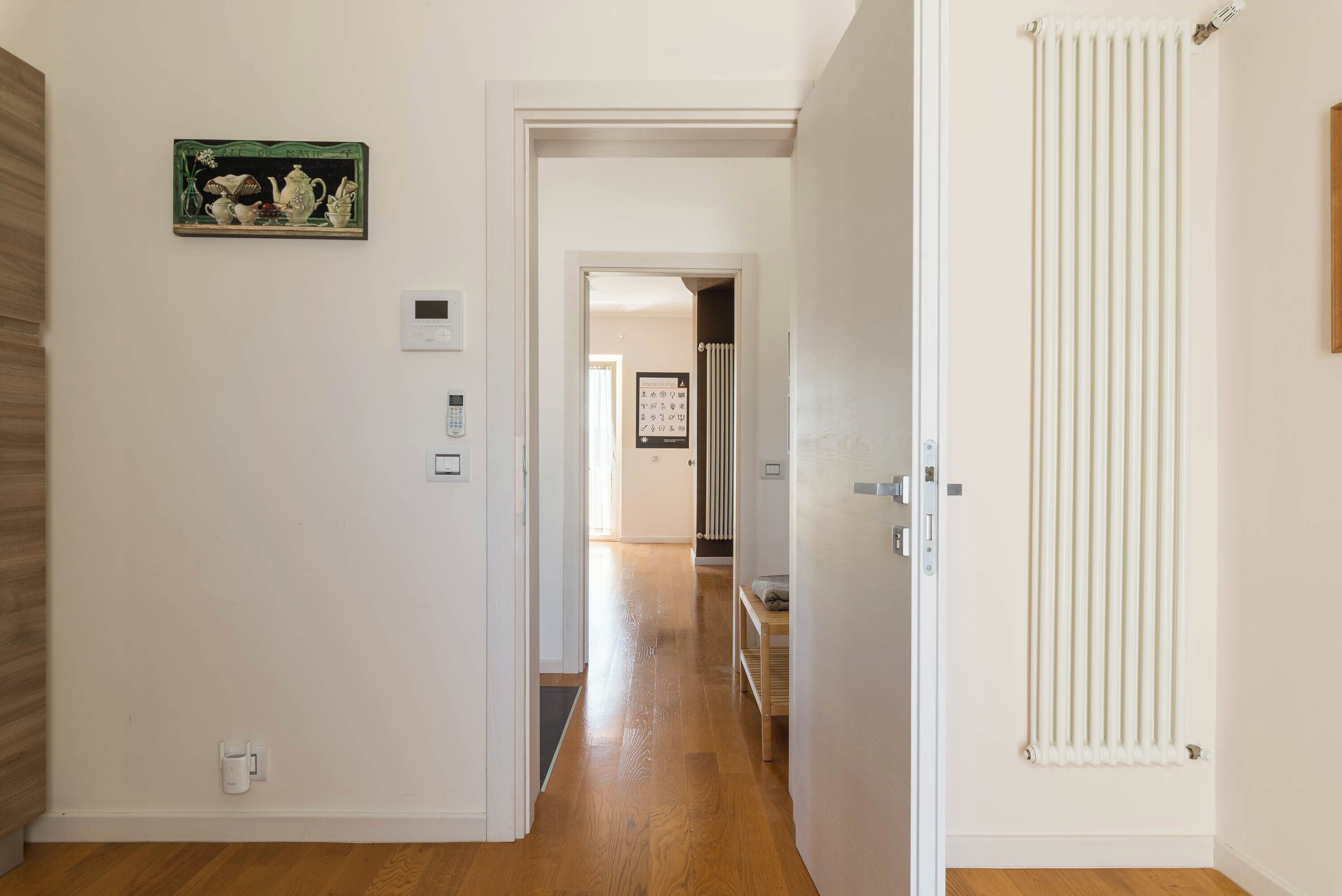 A hallway with a radiator, a door, and a wall-mounted thermostat.