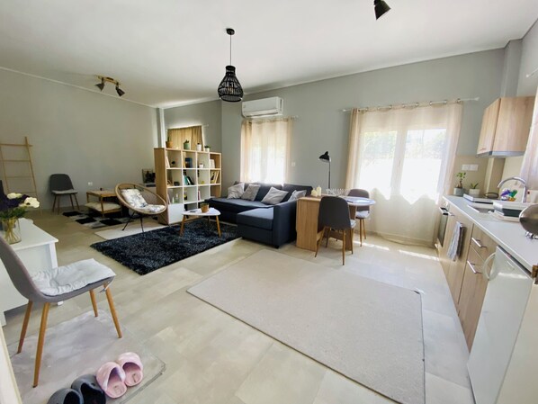 A modern living room with a sofa, a dining table, and a kitchen area.