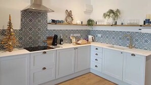 A modern kitchen with white cabinets, a stainless steel range hood, and patterned backsplash tiles. - Aberporth 2-bed Cottage , Sleeps 4 & Pet Friendly (Cardigan)