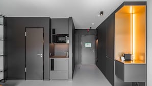 Un couloir moderne avec un coin cuisine, un grand miroir et un luminaire lumineux.