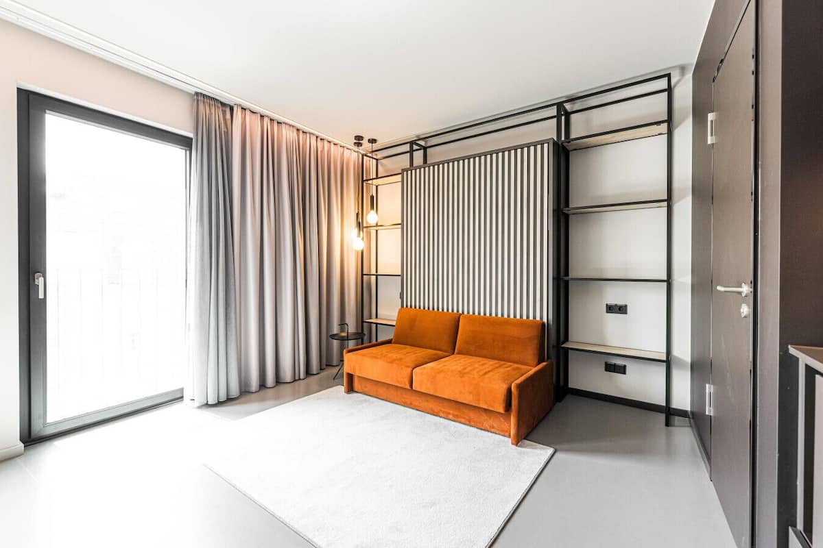 A modern bedroom with a sofa, a large wardrobe, and a sliding glass door.