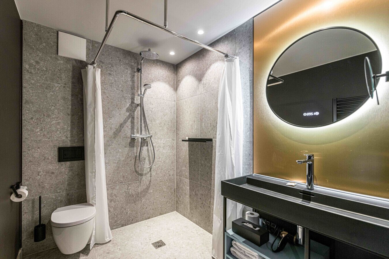 Un bagno moderno con doccia a filo pavimento, un WC, un lavandino con specchio e un porta asciugamani.