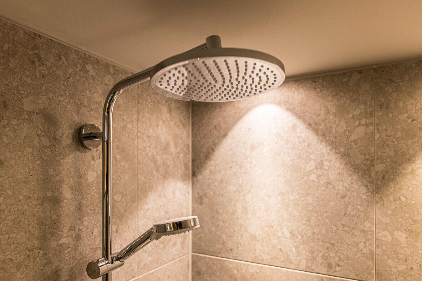 A modern shower with a rain showerhead and a handheld showerhead.