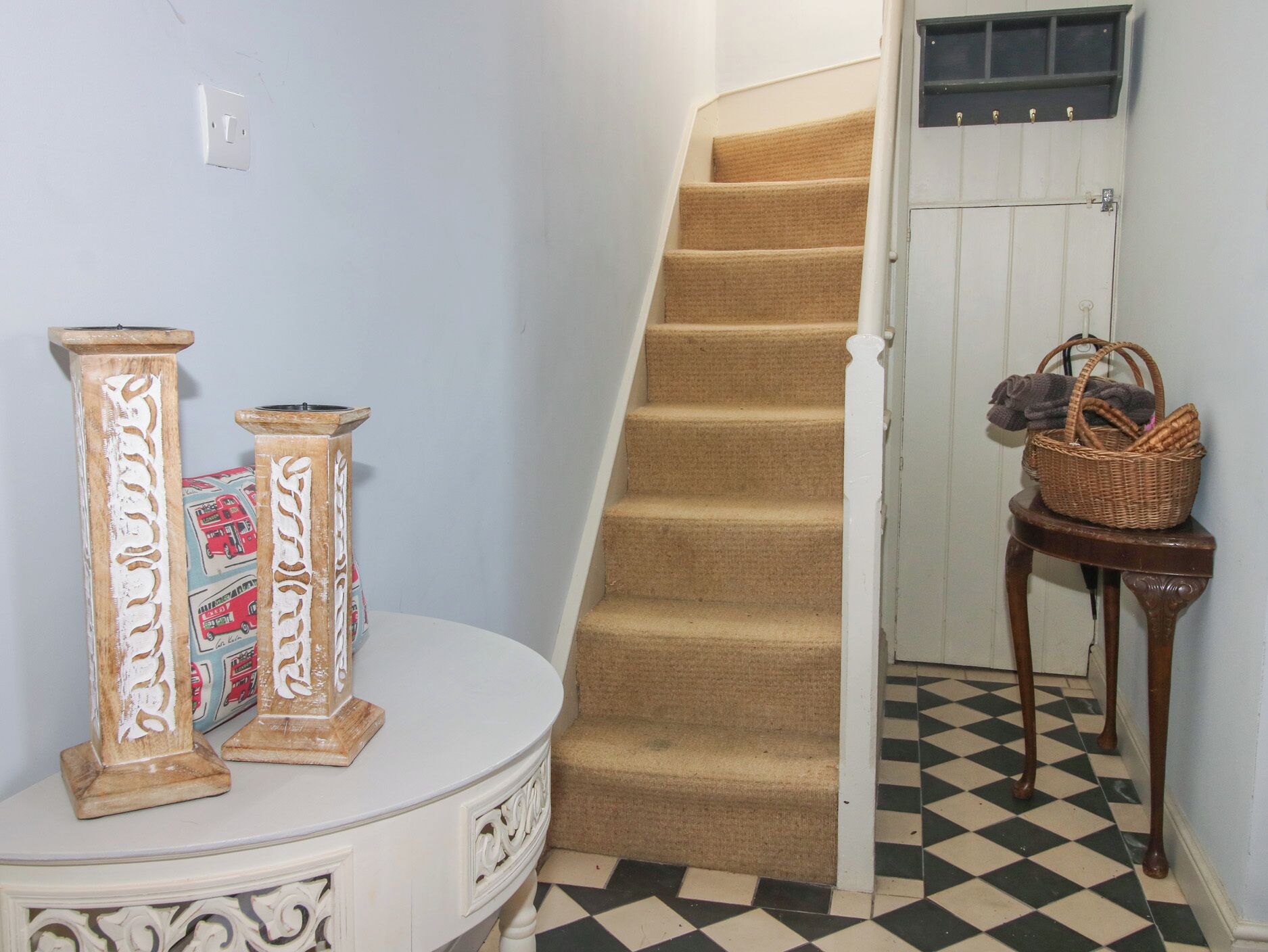 Una escalera con alfombra color beige, una puerta blanca con ventana y un piso a cuadros.