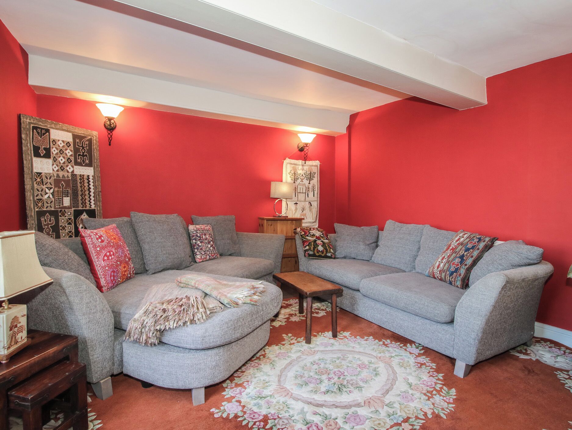 A living room with two grey sofas, a small wooden table, and a floral rug.