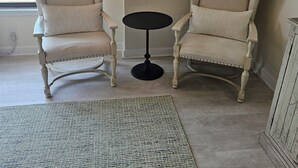A room with two armchairs, a small round table, and a textured rug.