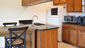 A kitchen with wooden cabinets, a white refrigerator, a microwave, and a sink.