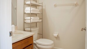 A bathroom with a toilet, a sink, a towel rack, and a toilet paper holder.