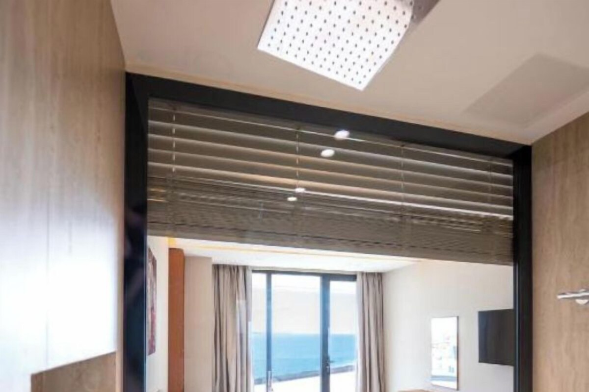 A modern hotel room with a large bed, a view of the sea, and a balcony.