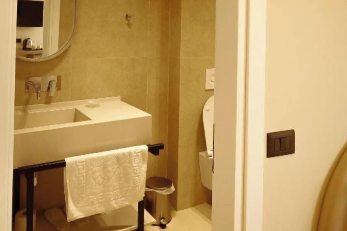 A bathroom with a sink, mirror, toilet, and a towel hanging on a rack.