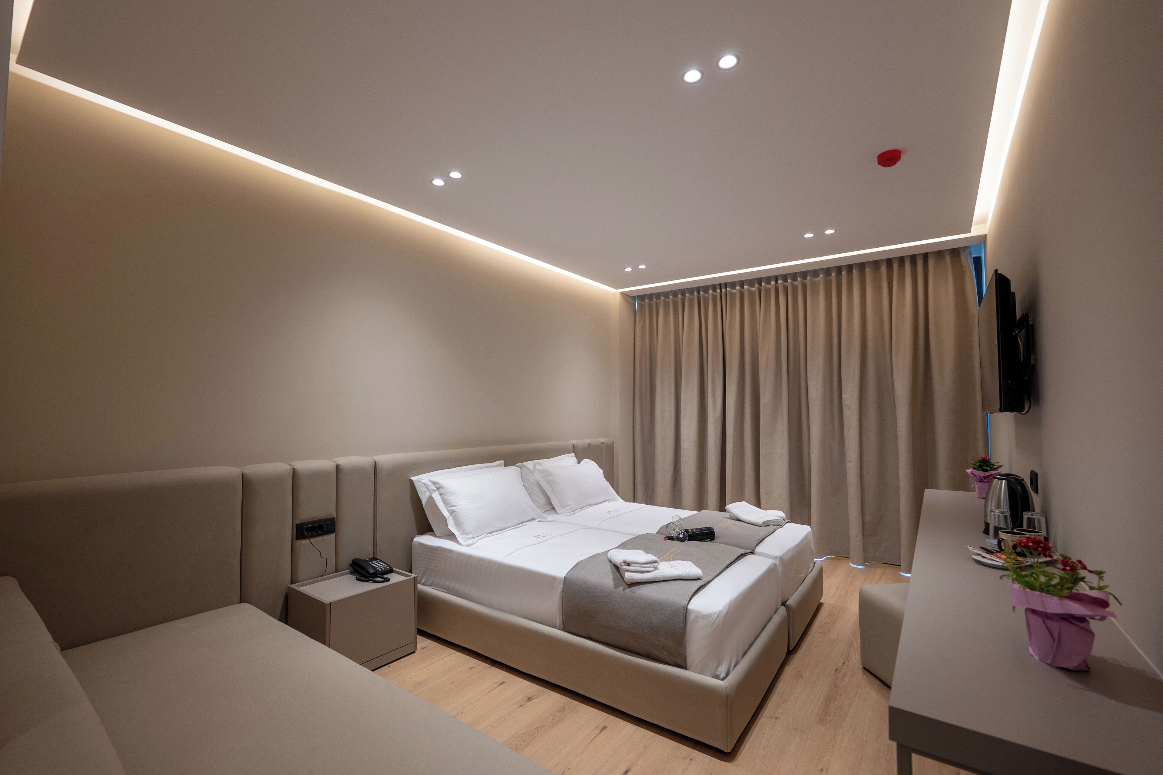 A modern hotel room with a large bed, bedside tables, a desk, and a TV mounted on the wall.