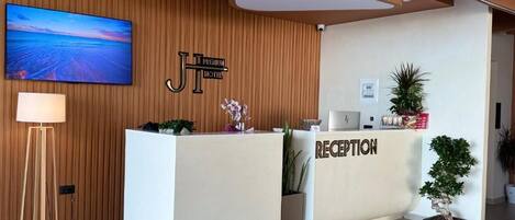 A hotel reception desk with a 'Premium Hotel' sign, a reception area, and a large TV screen displaying a beach scene.