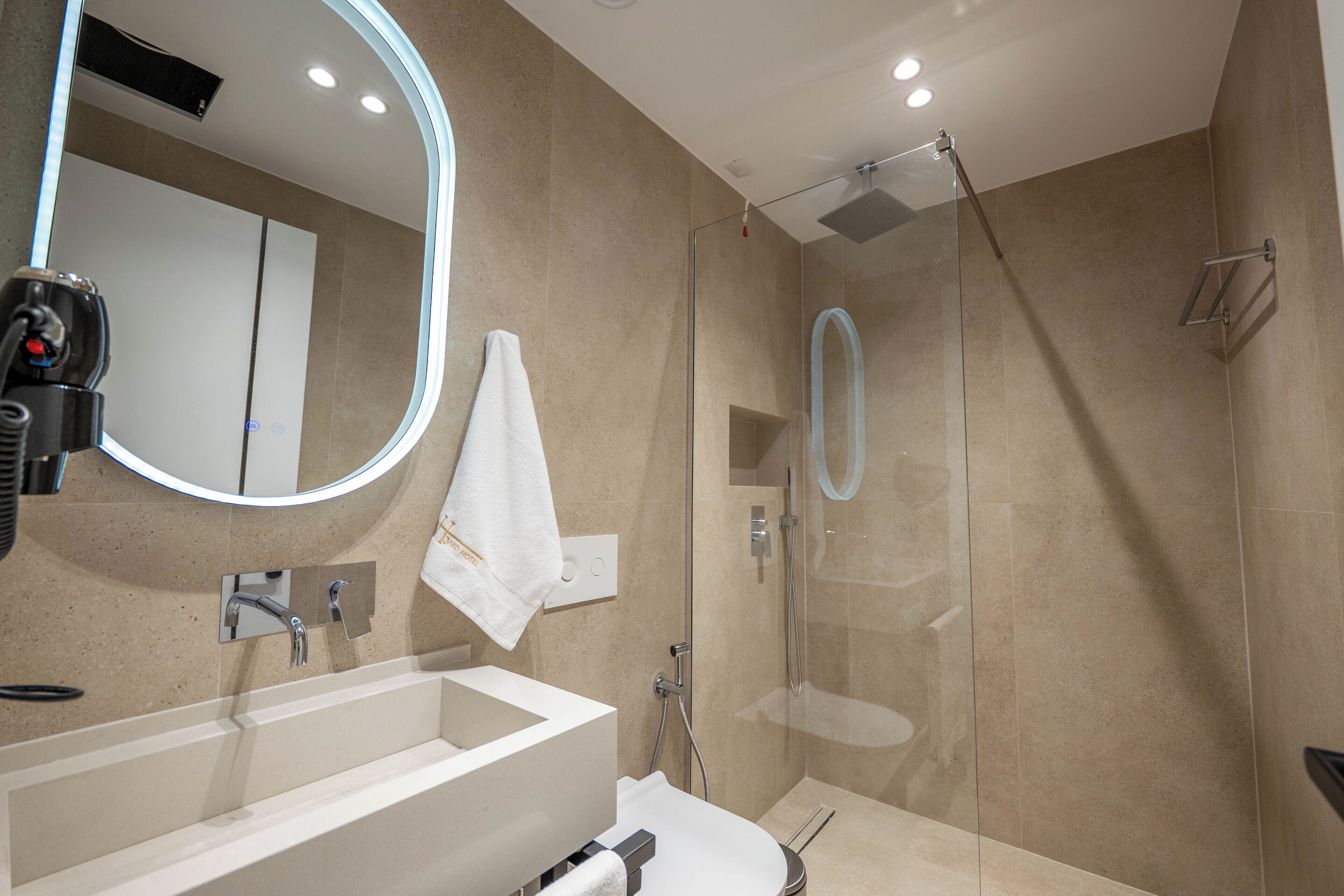 Un baño moderno con un espejo grande, una bañera, una ducha y una toalla colgada en la pared.