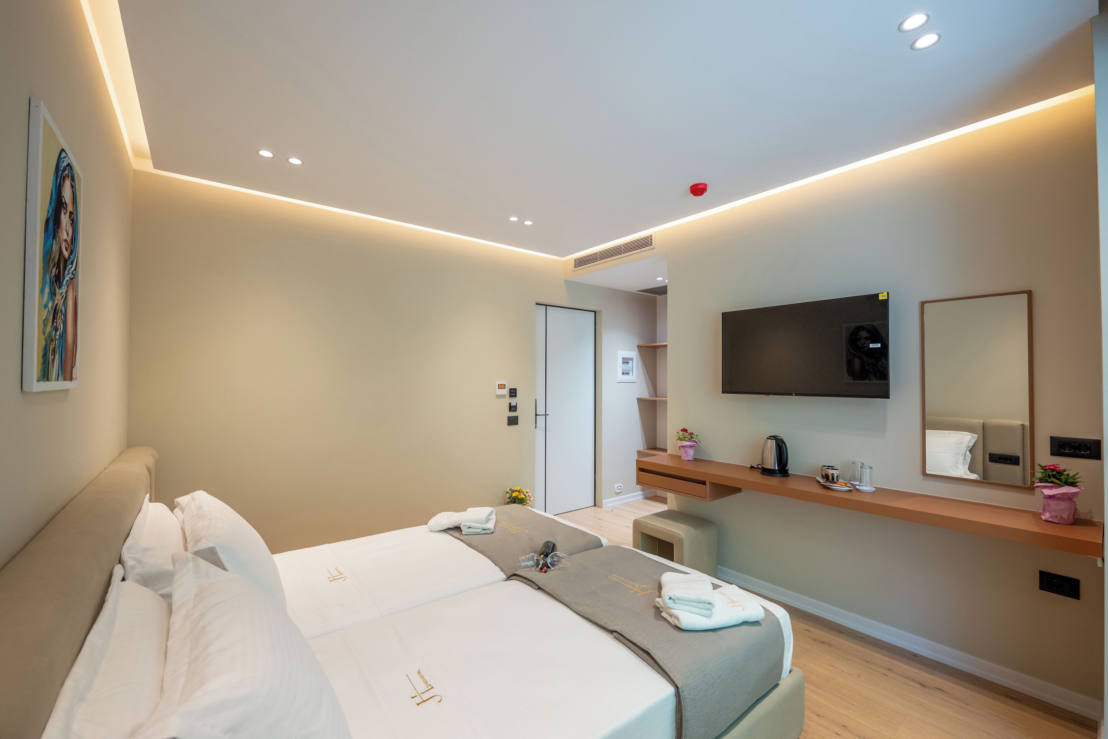 Een moderne hotelkamer met een groot bed, een aan de muur bevestigde televisie en een klein zitgedeelte.