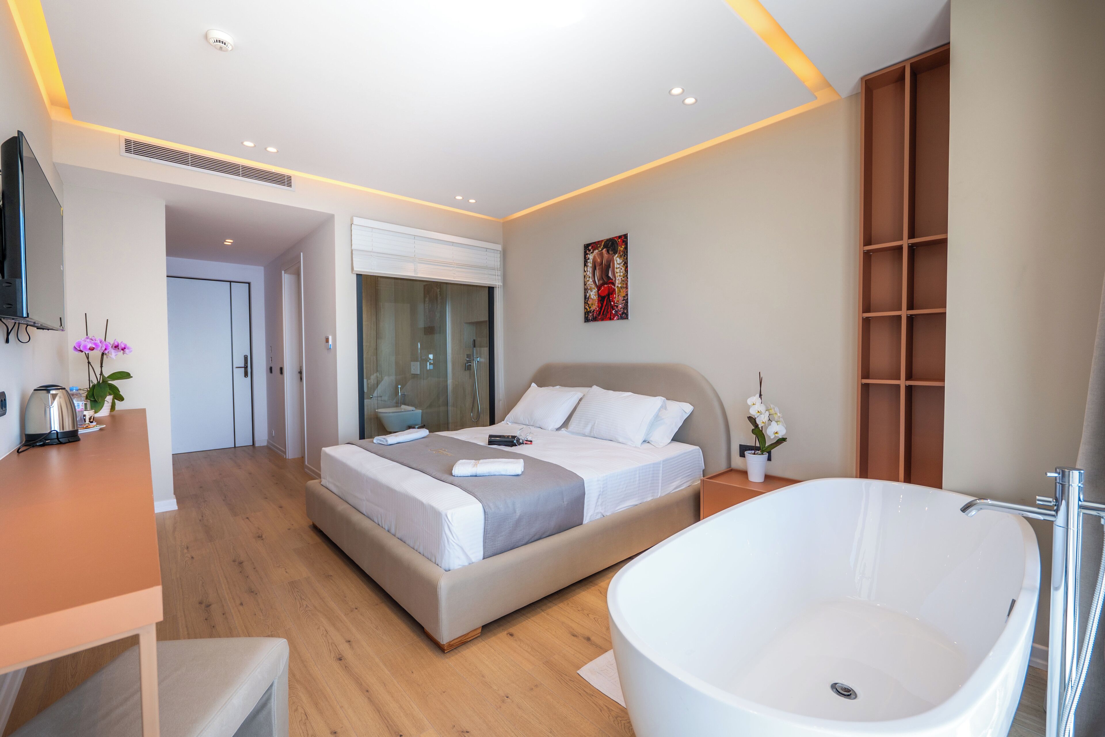 Ein modernes Schlafzimmer mit einem großen Bett, einer Badewanne und einem Schreibtisch mit einer Pflanze.