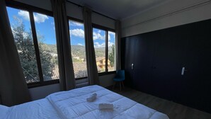 A hotel room with a bed, a chair, and a view of the outdoors. - Cubez Hostel Viladrau (Viladrau)