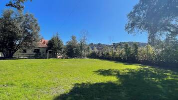 Un campo cubierto de césped con árboles y un edificio al fondo.