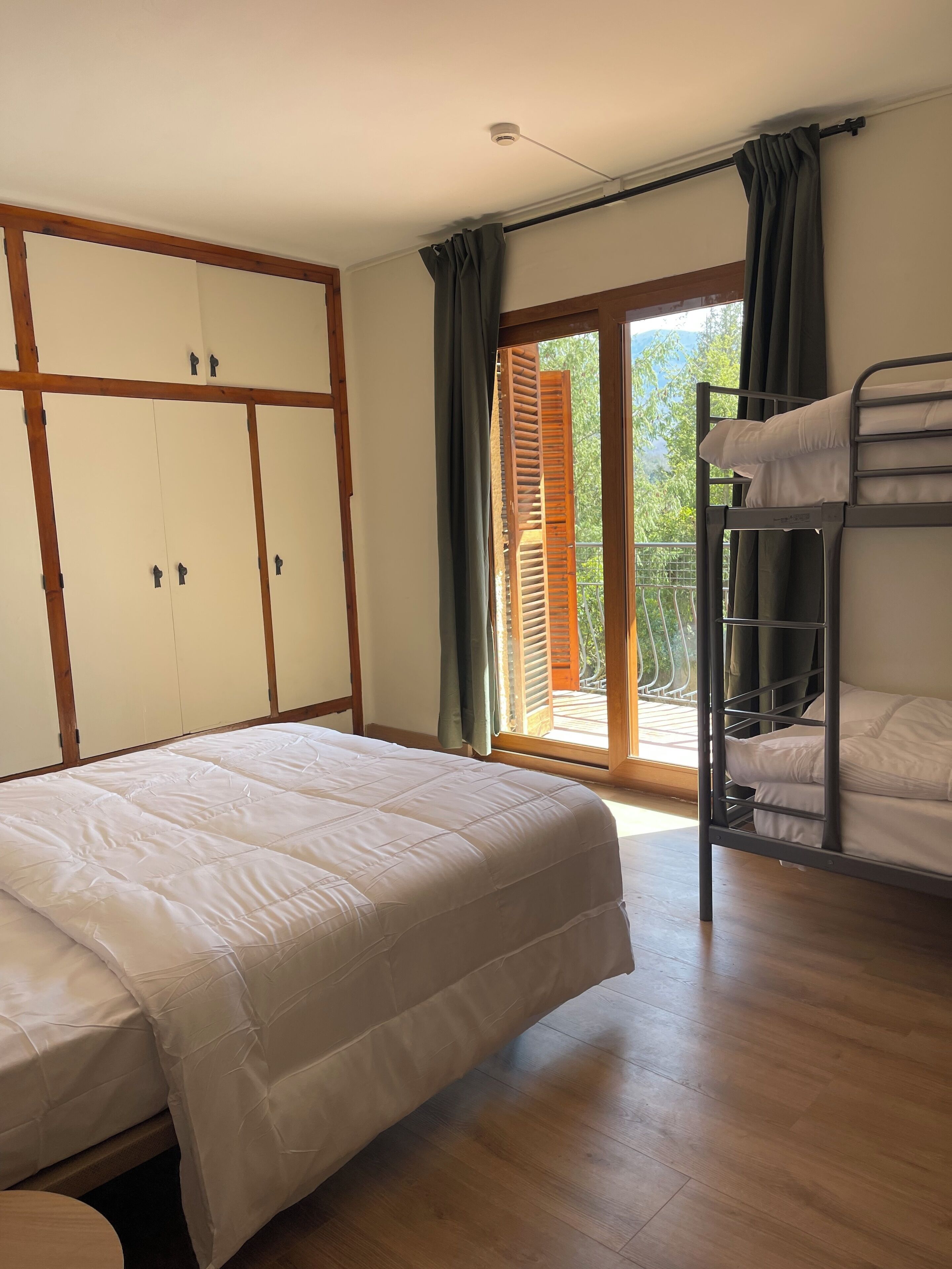 A room with a bunk bed, a large wardrobe, and a sliding glass door leading to an outdoor area.