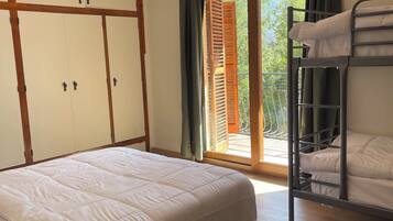 A room with a bunk bed, a large wardrobe, and a sliding glass door leading to an outdoor area.
