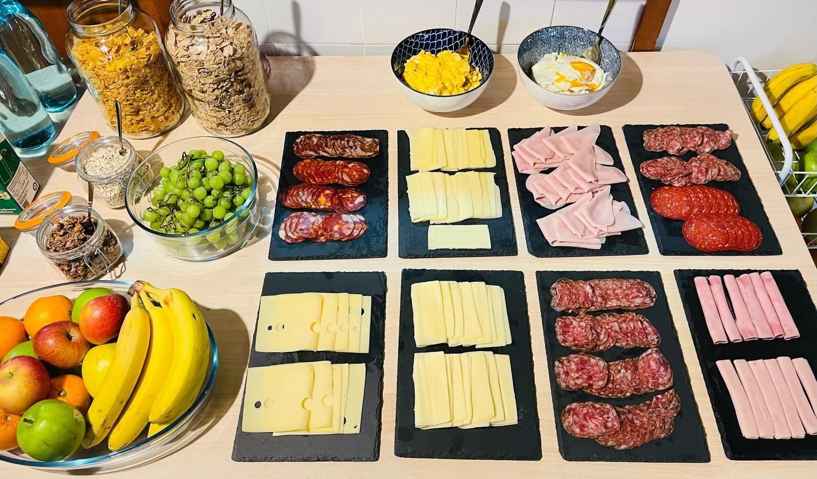 Una mesa con diversos alimentos, incluyendo queso, carnes y frutas.