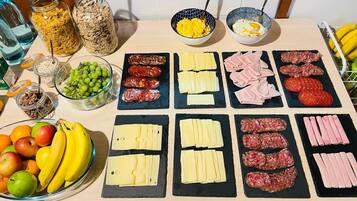 Una mesa con diversos alimentos, incluyendo queso, carnes y frutas.