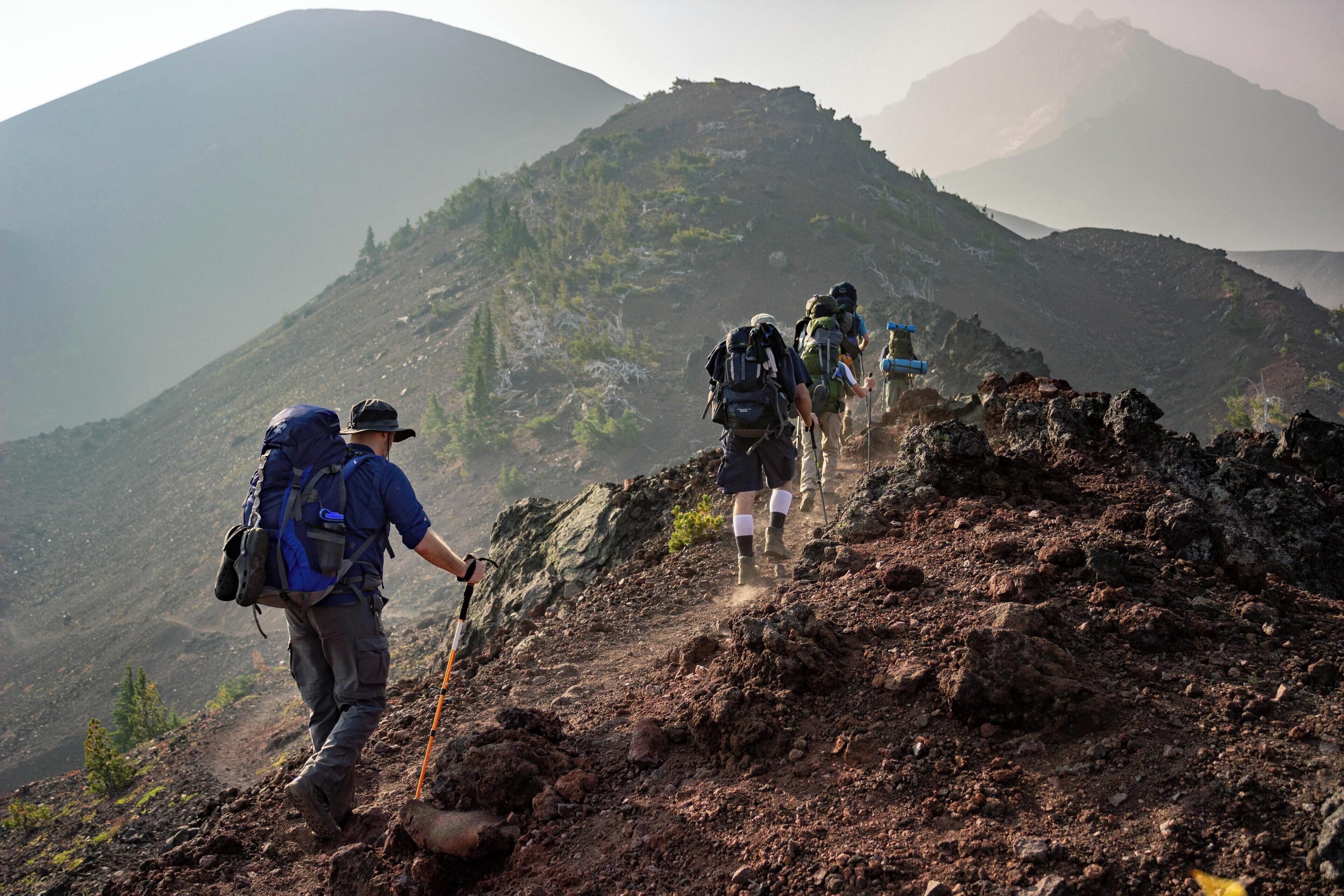 A group of hikers on a rocky mountain trail with a view of distant mountains.