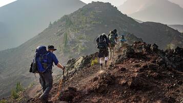 A group of hikers on a rocky mountain trail with a view of distant mountains.