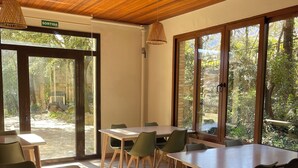 A dining area with wooden tables and chairs, large windows, and a wooden ceiling. - Cubez Hostel Viladrau (Viladrau)