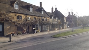 A row of traditional stone buildings with pitched roofs, a sidewalk, and a grassy area. - Cosy 3 Bedroom Lodge at Avonvale Holiday Park (Evesham)