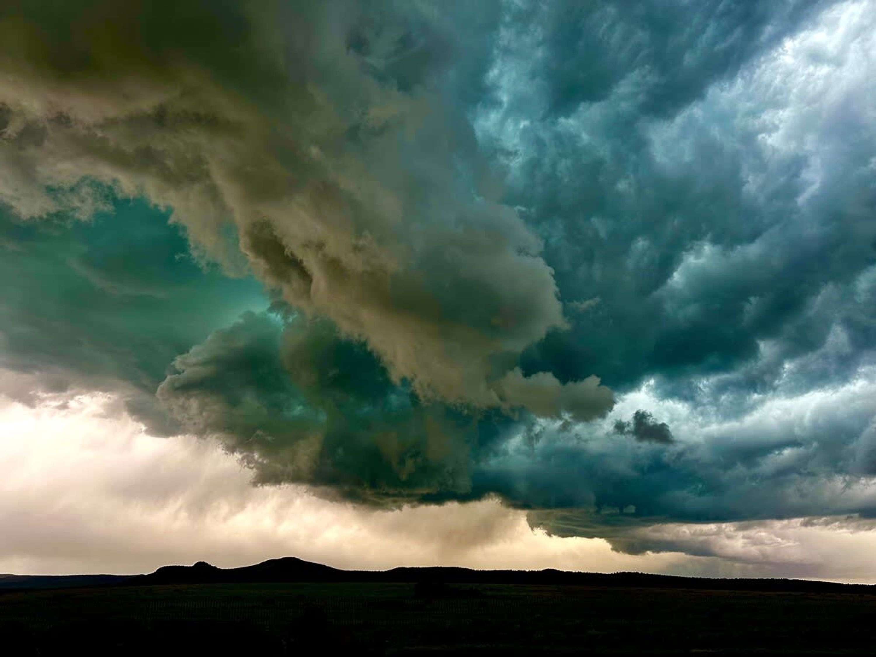 A stormy sky with dark clouds over a flat landscape.