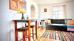 Un salón acogedor con una mesa de madera, un sofá y una alfombra colorida.