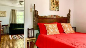 Un dormitorio con cabecera de madera, colcha roja y almohadas estampadas.