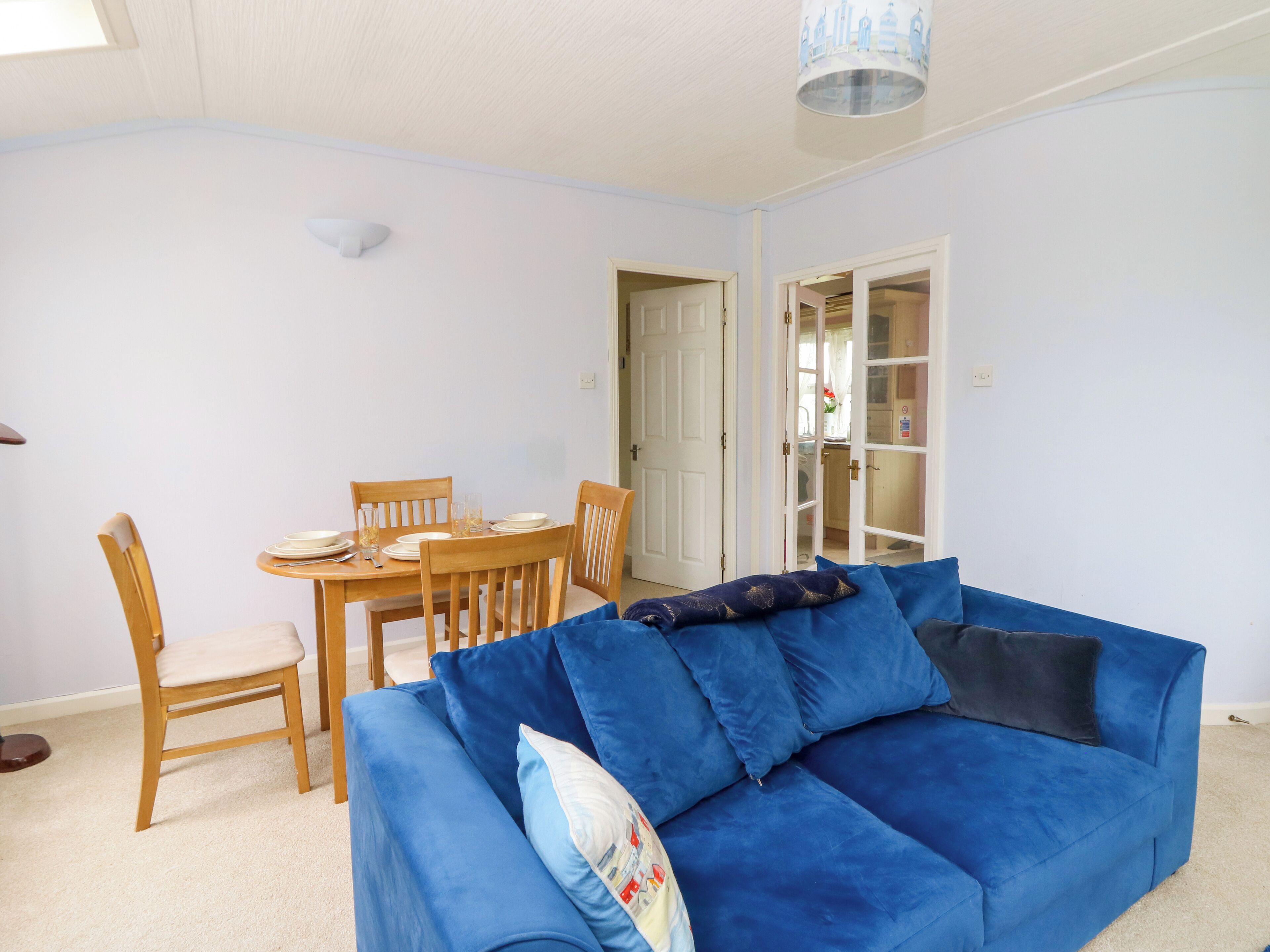 A living room with a blue sofa, wooden dining table, and chairs.