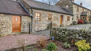 A stone building with a wooden door and a metal gate, surrounded by a stone wall and gravel path. - The Stables at Brambles Farm - Sleeps 2, Wifi (Leek)