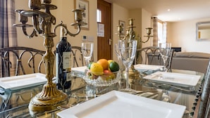 A dining table set with white plates, a glass bowl of fruit, and ornate candelabras.