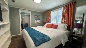 A bedroom with a bed, a nightstand, a lamp, and a window with curtains. - Stylish home in Little Rock (Little Rock)