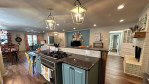 A kitchen with a central island, wooden flooring, and pendant lighting. - Stylish home in Little Rock (Little Rock)