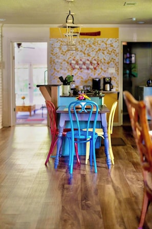A dining area with a table and chairs, a kitchen in the background, and a wooden floor. - Stylish home in Little Rock (Little Rock)