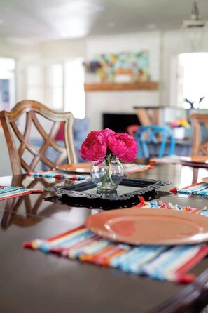 A dining table with a vase of flowers, placemats, and a black placemat. - Stylish home in Little Rock (Little Rock)